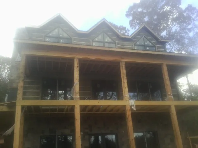 Dormers and porch framing on a large log home under construction — Roof Coating work by our crew in Macon