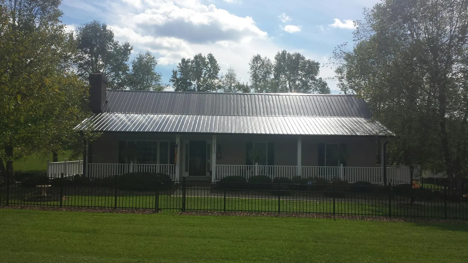 Gray metal roof on a brick ranch with a full width front porch — Gutter Guard Installation work by our crew in Macon