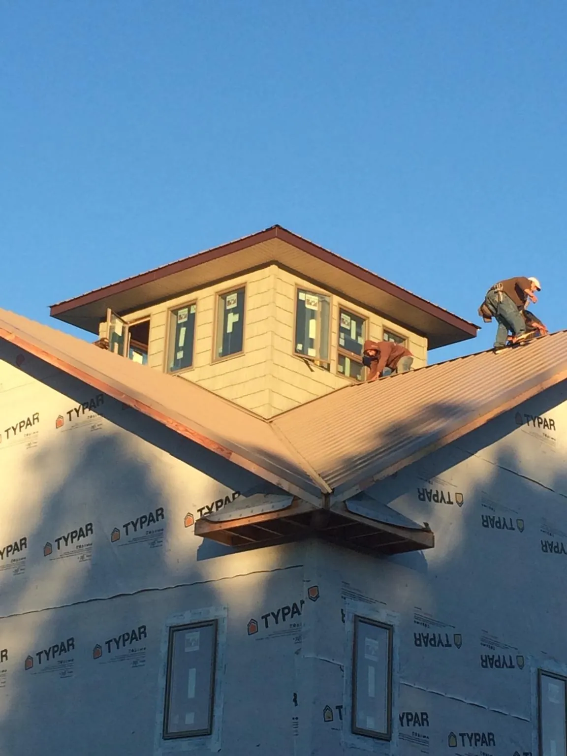 Roofers working around a rooftop cupola on a new metal roof at sunset — Roof Waterproofing in Macon by Roofing Brothers